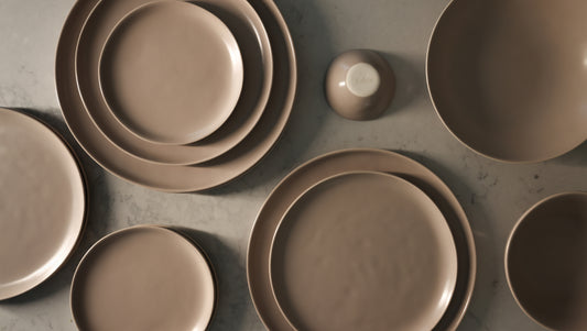 Desert Taupe matte stoneware Fable plates and bowls arranged from above on a marble surface