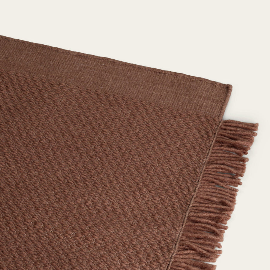 Brown woven blanket with frayed edge on a light beige background #sunsettan