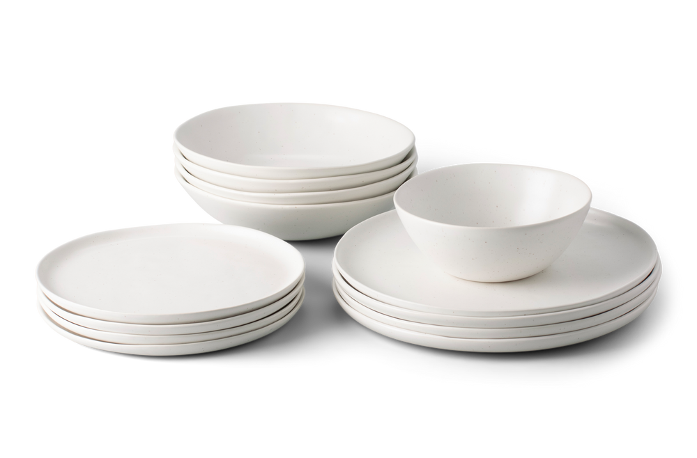 White dinnerware set with plates and bowls arranged in stacked groups on a white background