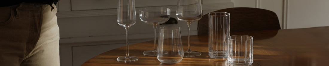 Assortment of wine glasses and tumblers arranged on a wooden dining table