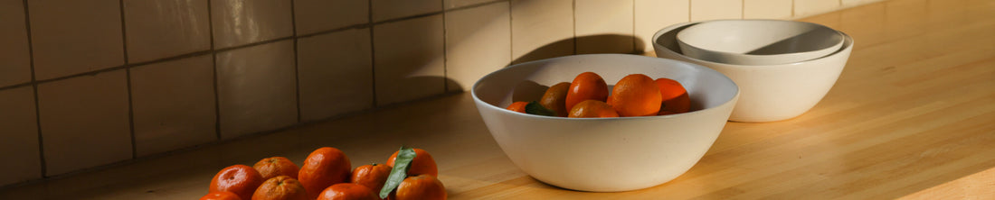 White ceramic serving bowl filled with tangerines on a wooden kitchen counter