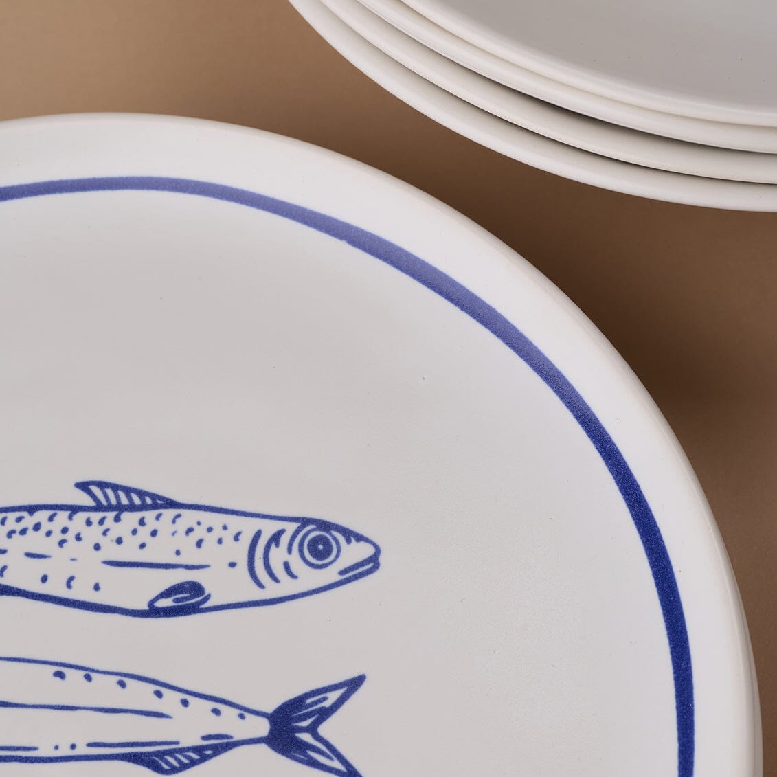White plate with blue fish design on a brown background