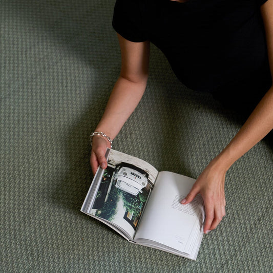 Person holding an open book on a textured green surface #sagegreen