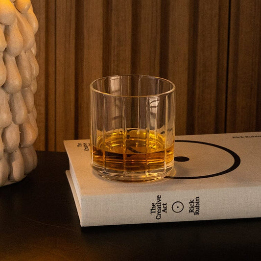 Glass of amber liquid on a book with a warm-toned background #clear