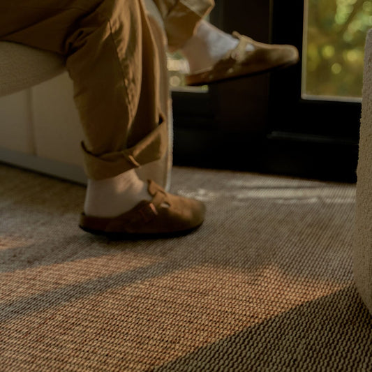 Person wearing brown shoes and beige pants on a patterned carpet #burntsienna