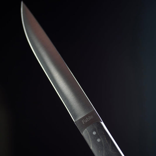 Knife blade with 'Fable' branding on a dark background #black
