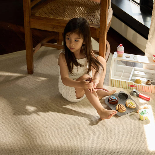 Young girl playing with toy baking set on a Dune Gray rug #dunegray